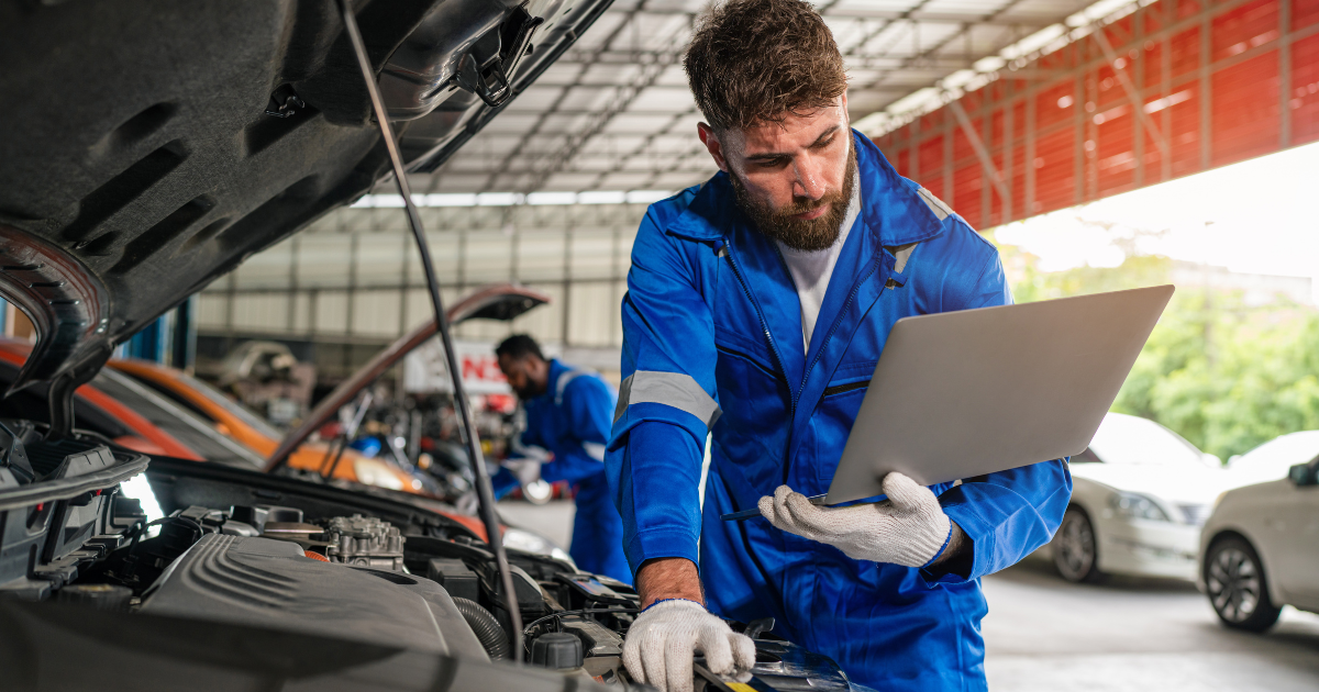 Powerful Auto Repair Software Scheduling: Use It or Lose It 6 car mechanic working on a car and holding a tablet and using Auto Repair Software Scheduling