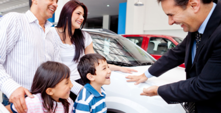 auto dealer with a family in the shop with their new car.