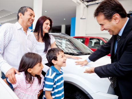 auto dealer with a family in the shop with their new car.