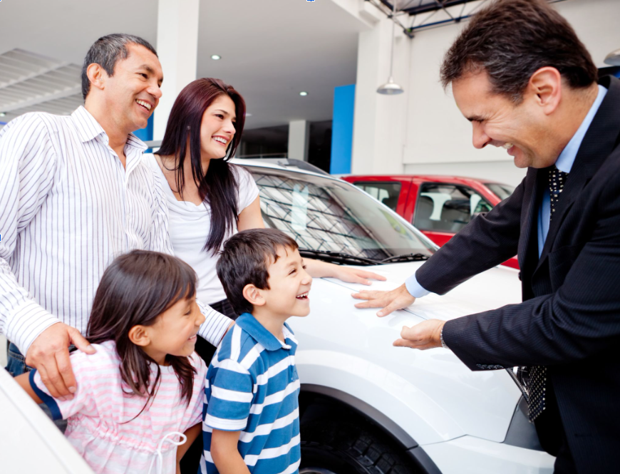 auto dealer with a family in the shop with their new car.