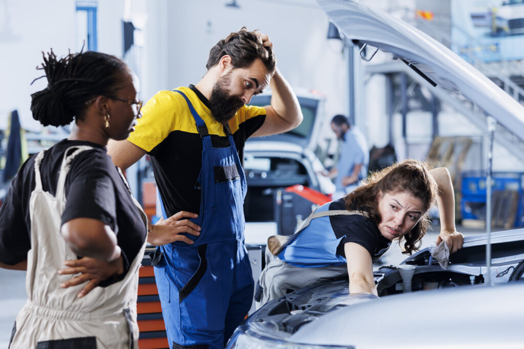 Powerful Auto Repair Software Scheduling: Use It or Lose It 2 mechanics looking frustrated in font of a car they are working on.